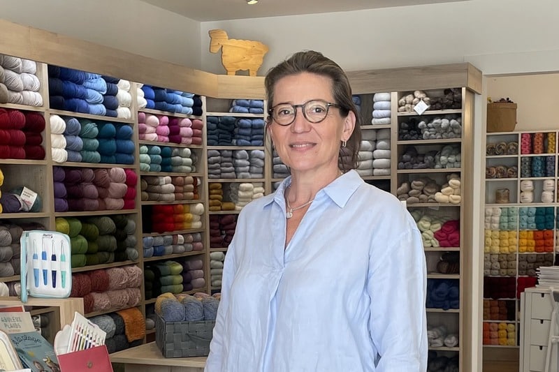 Depuis début mai, un tout nouveau et très beau magasin baptisé « Chas-Maille » au 13 rue Jules Ferry propose aux amateurs de tricot, de broderie, de crochet… toute la panoplie pour s’adonner à leurs travaux d’aiguille préférés. Stéphanie Lechevalier s’est lancée dans cette belle aventure, aidée en cela par Paule et Michèle, mercières bien connues à Vaison (voir notre publication récente). « J’ai travaillé pendant 32 ans dans la banque et l’idée de faire autre chose a germé dans ma tête il y a 25 ans… Mais c’était un doux rêve. Aujourd’hui, avec moins de pression financière, j’ai voulu faire quelque chose qui me tenait vraiment à cœur. Et l’opportunité a été bien sûr le départ de Paule. D’autant que la ville de Vaison me tenait à cœur, car j’y ai constaté un beau dynamisme et une belle ambiance commerciale », explique Stéphanie, tout sourire. Et apparemment, elle aussi a constaté que, depuis le COVID, l’image des travaux d’aiguille a été largement dépoussiérée et les jeunes surtout sont revenus au crochet, mais aussi au tricot, à la broderie. Selon elle, les amateurs de travaux d’aiguille ont vraiment besoin de toucher la matière, expérimenter la douceur, la souplesse, la couleur de la laine, du fil : ce côté charnel de la matière est essentiel. « Derrière une boutique, il y a aussi l’idée de créer et de garder du lien autour d’un plaisir partagé » déclare la commerçante en expliquant vouloir lancer des cours d’initiation et des ateliers pour les enfants (bon moyen d’échapper aux écrans…) mais aussi pour les adultes. Un « Café tricot » y est déjà organisé tous les vendredis après-midi avec des tricoteuses de Nyons et de Vaison. « Un atelier peut permettre de donner l’envie ou de redonner le déclic en se rappelant ce que l’on a fait étant jeune. Il est même prouvé que le tricot a un effet thérapeutique, car se concentrer sur une activité manuelle peut aider : les écoles, les hôpitaux, les EHPAD, l’expérimentent. » Et de conclure : « je suis heureuse, j’ai le sourire et je rencontre des sourires. Je souhaite que mon magasin soit un diffuseur de bonheur. » Photo : Stéphanie Le Chevalier, en son magasin « diffuseur de bonheur »